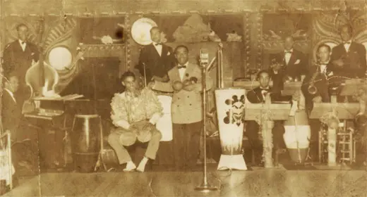 Daniel Garcia's father, Jose Garcia, playing the bongos, with Machito of the Machito Orchestra. Circa: early 1940s